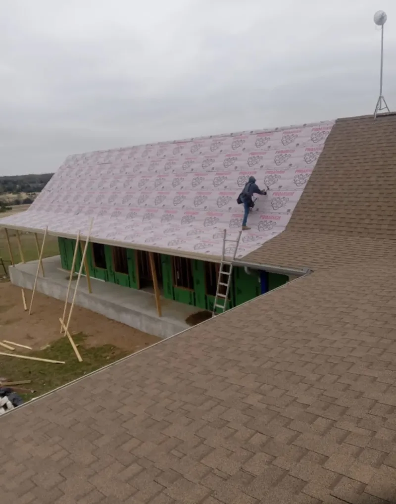 Worker preparing underlayment for a metal roof installation in Bryan